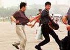 Published on 7/21/2001 A man’s bag and glasses go flying as a policeman, right, catches up with him after chasing him through Beijing’s Tiananmen Square Friday, July 20, 2001. The man was wrestled to the ground and taken away in a police van. At least eight people were detained in the square Friday morning, the second anniversary of the crackdown on the Falun Gong [group] which was banned two days later on July 22, 1999. 