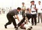 Published on 7/21/2001 A man’s bag and glasses go flying as a policeman, right, catches up with him after chasing him through Beijing’s Tiananmen Square Friday, July 20, 2001. The man was wrestled to the ground and taken away in a police van. At least eight people were detained in the square Friday morning, the second anniversary of the crackdown on the Falun Gong [group] which was banned two days later on July 22, 1999. 