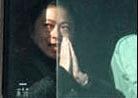 Published on 5/20/2000 法轮功女学员被押上警车后从容地微笑着向窗外双手合十。